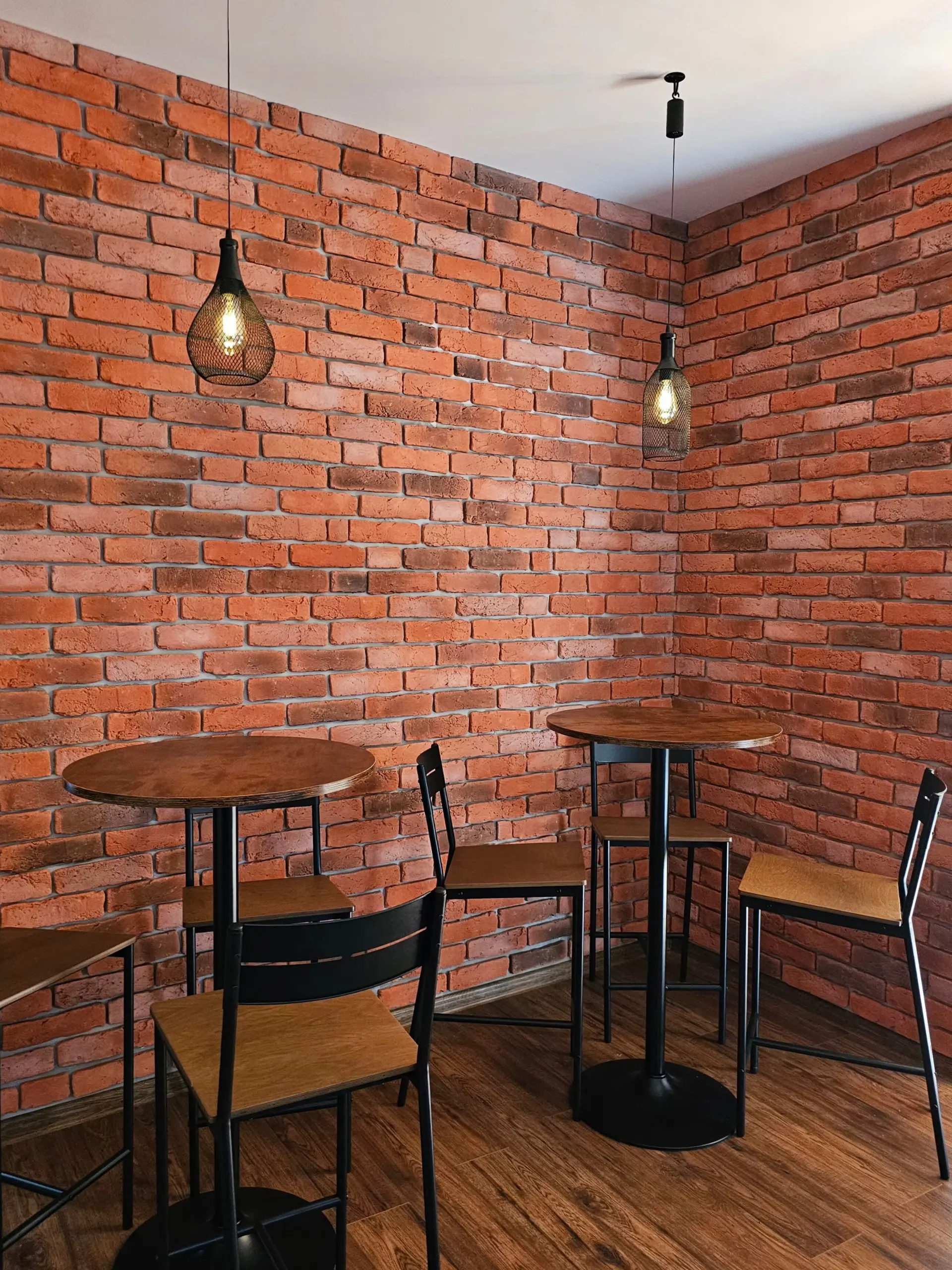 Rustic seating area with exposed brick walls, hanging pendant lights, and wooden tables at The Wine Shed, Market Harborough